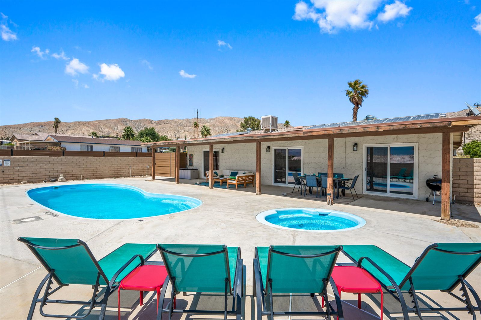 Backyard with kidney-shaped pool, hot tub, loungers and mountain views