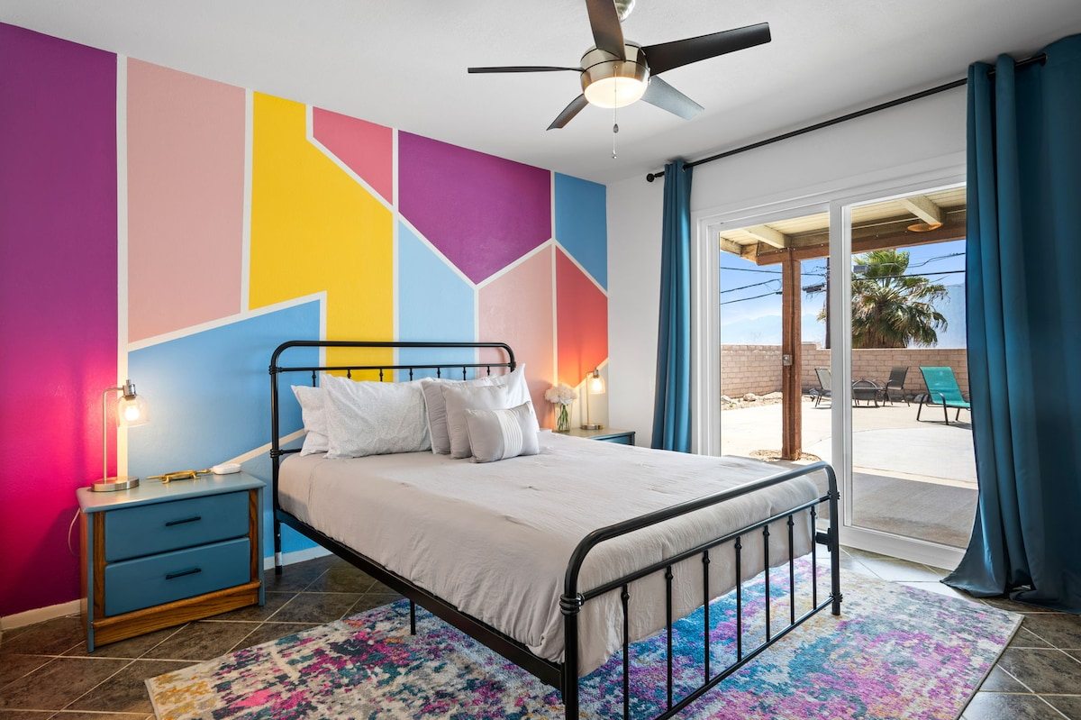 Queen bedroom with color-block mural and sliding door to the backyard