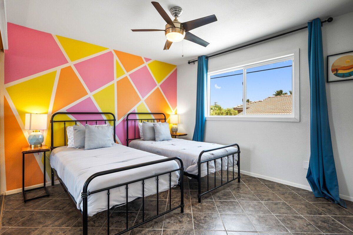 Twin bedroom with pink and yellow geometric mural wall