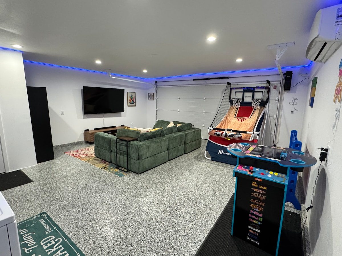 Game room with 75-inch TV, sectional and arcade games under LED lighting