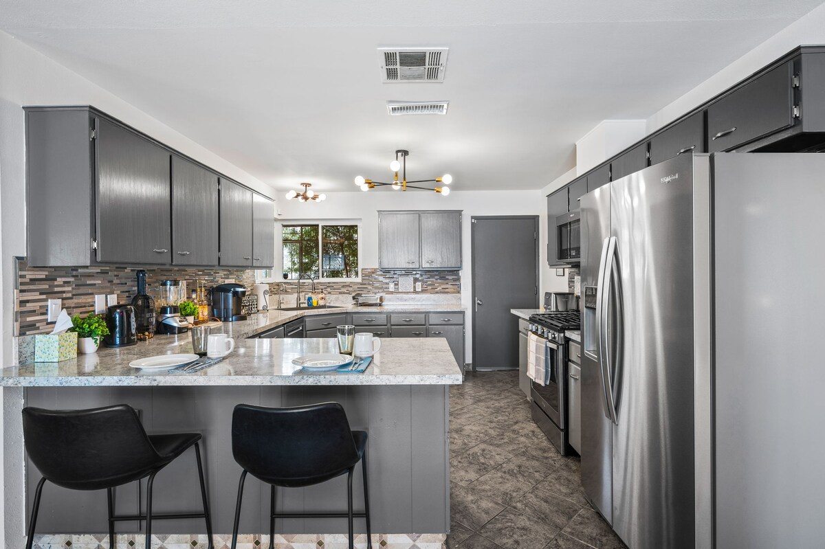 Gray kitchen with gas range, peninsula seating and stainless fridge