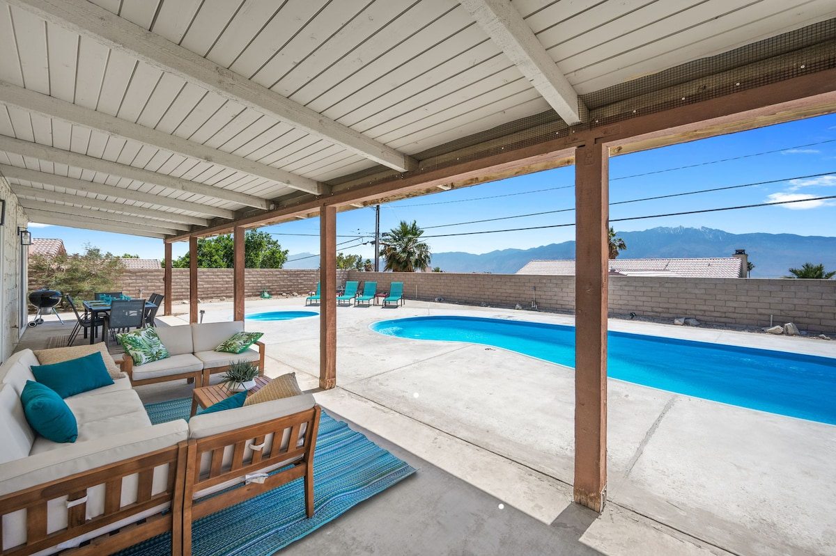 Shaded pergola lounge seating facing the pool and mountains